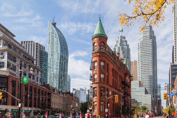 Red brick Gooderham Building with new buildings in background in Toronto downtown.