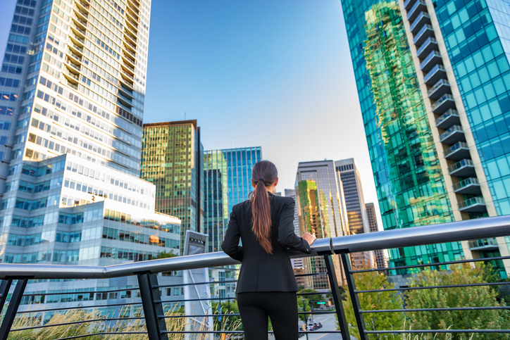 Business woman in city center looking at view of skyline skyscrapers in Vancouver downtown , Canada. Businesswoman from the back pensive thinking about success and future in career and job